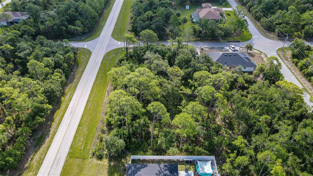 An aerial view shows a wooded residential lot situated between two paved roads — 1213 BISCAYNE DRIVE, PORT CHARLOTTE, FL
