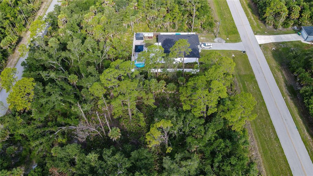 An aerial view shows a house with a pool and fenced yard surrounded by trees — 1213 BISCAYNE DRIVE, PORT CHARLOTTE, FL