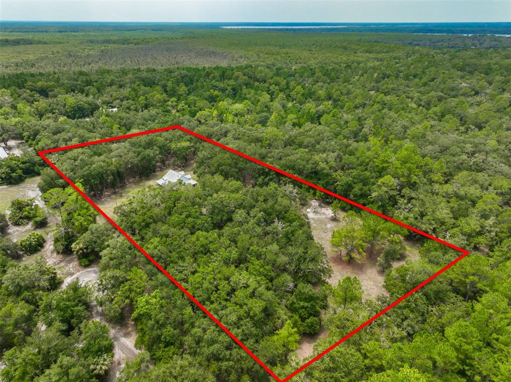 An aerial view shows a house nestled within a large, wooded, rectangular property lot — 2680 W COUNTY ROAD 2006 W, BUNNELL, FL