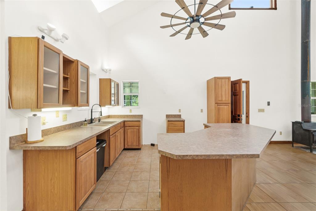 A kitchen with wood cabinets, laminate countertops, tile flooring, and a vaulted ceiling — 2680 W COUNTY ROAD 2006 W, BUNNELL, FL
