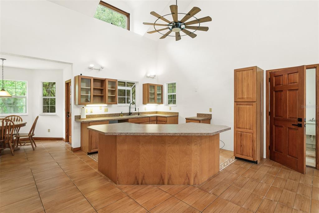 A kitchen with wood cabinets, a peninsula island, and tile flooring under a vaulted ceiling — 2680 W COUNTY ROAD 2006 W, BUNNELL, FL