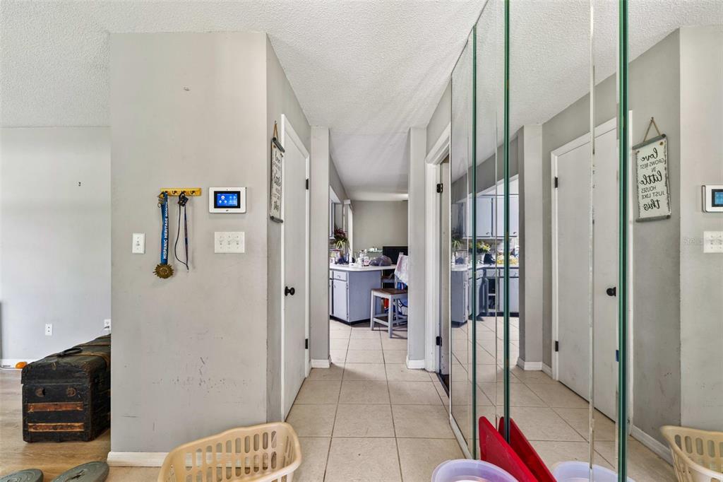 A hallway with tile flooring leads to a kitchen featuring a central island — 623 WOOD DRIVE, POINCIANA, FL
