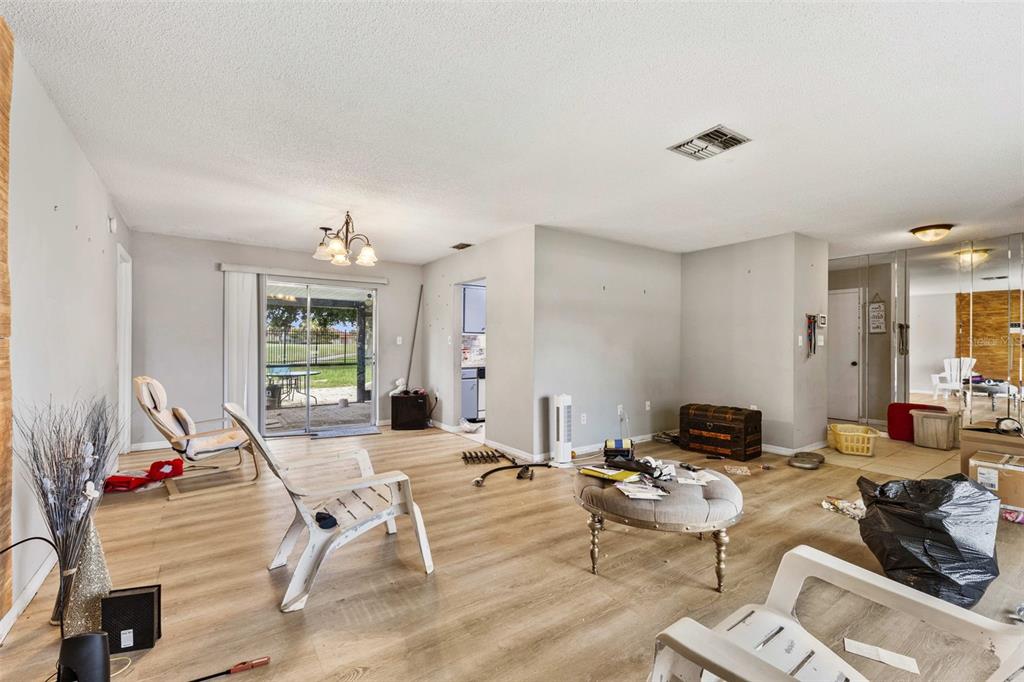 An open living area features light wood-look flooring, a sliding glass door, and neutral walls — 623 WOOD DRIVE, POINCIANA, FL