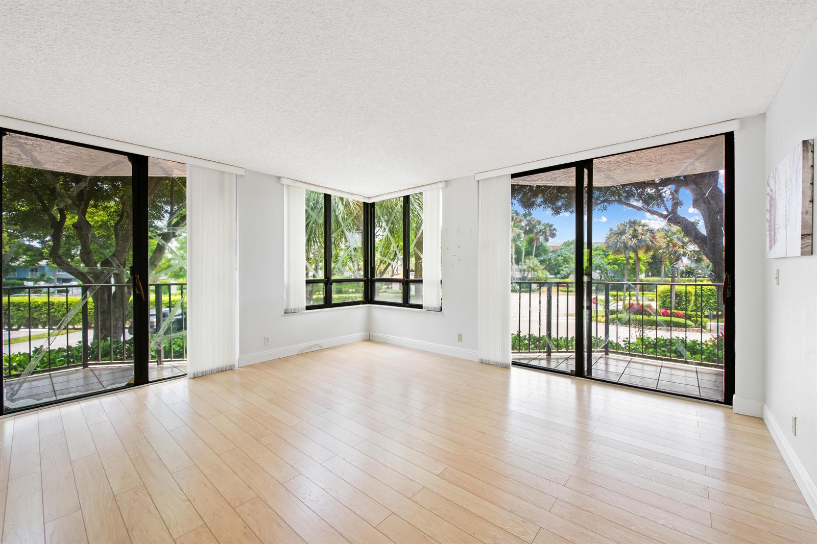 An empty living room features light wood flooring, white walls, and large sliding glass doors — 799 Jeffery Street # 201, Boca Raton FL 33487, BOCA RATON, FL