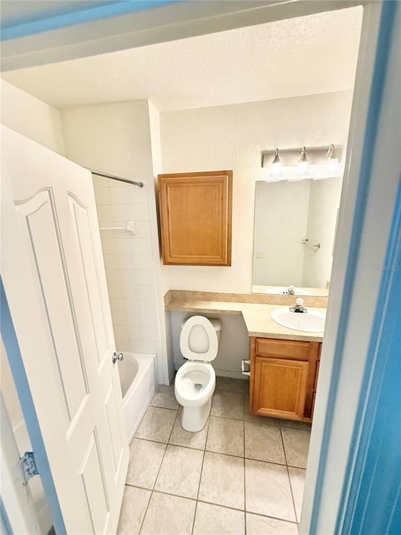 A bathroom features a white toilet, a wooden vanity with a sink, and a shower-tub combo — 6137 METROWEST BOULEVARD UNIT 306, ORLANDO, FL