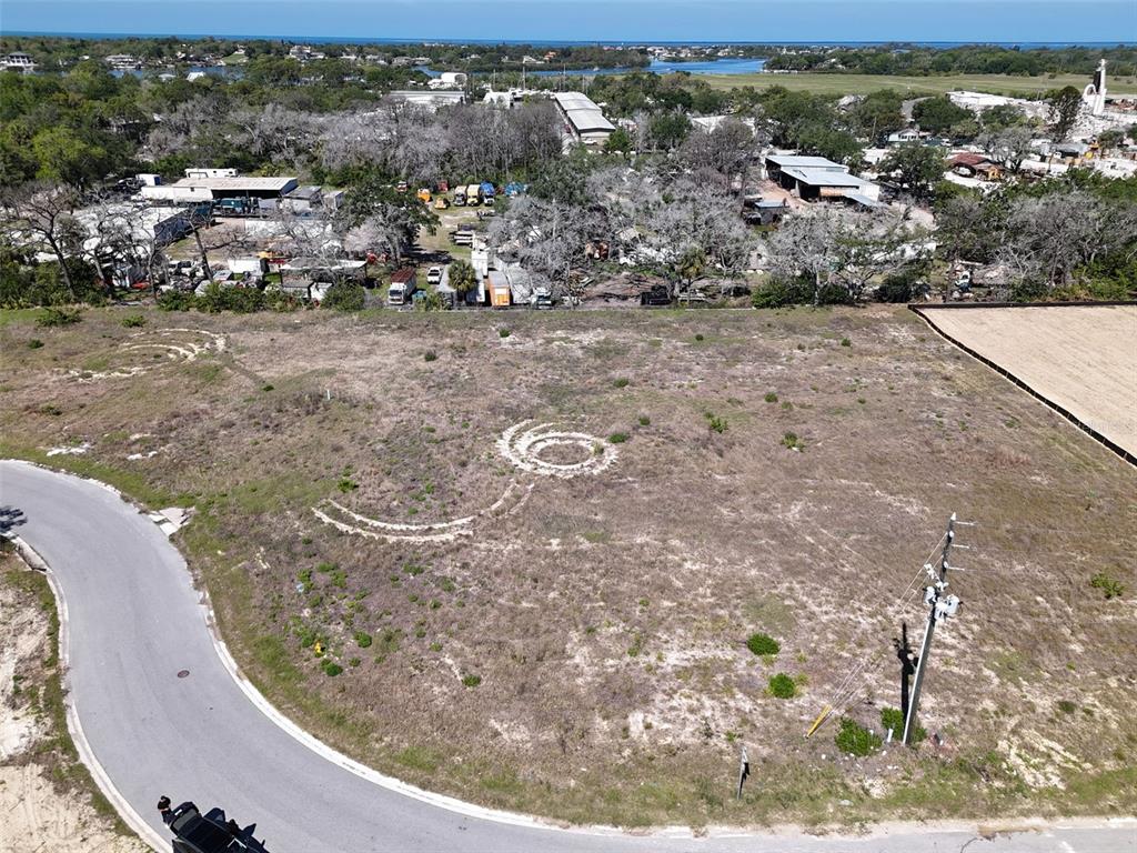 An aerial view shows a vacant, grassy lot with tire tracks and a utility pole — 1484 NORTH BEND DRIVE, TARPON SPRINGS, FL
