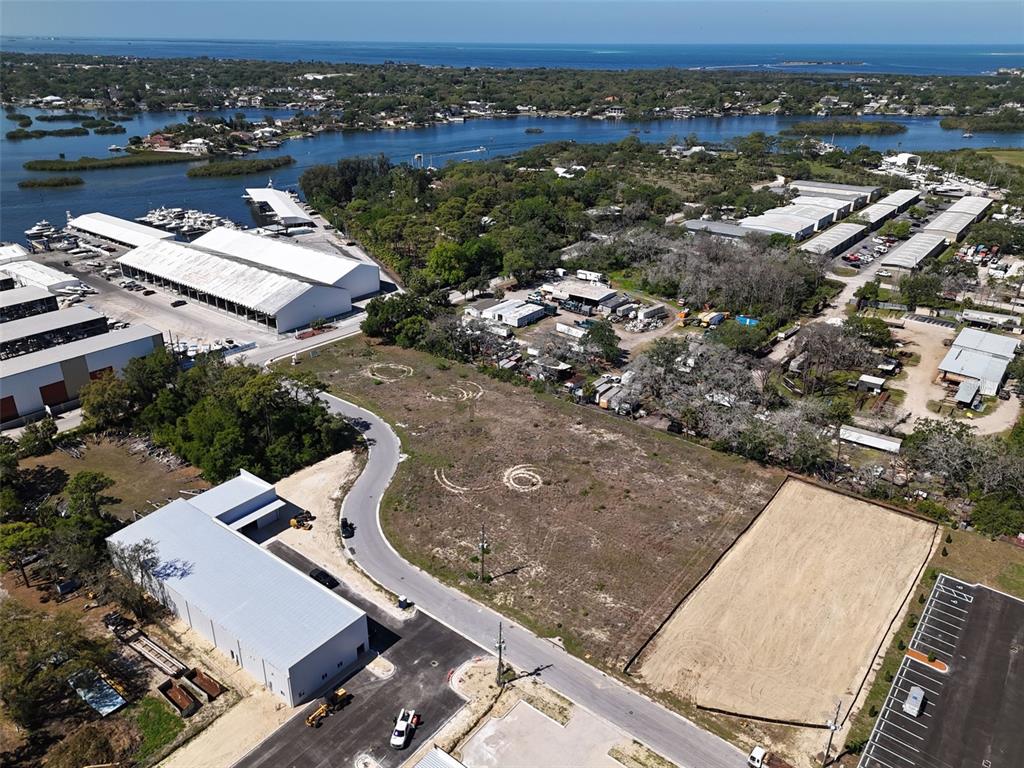 An aerial view shows a vacant lot, surrounding industrial buildings, and a nearby waterfront — 1484 NORTH BEND DRIVE, TARPON SPRINGS, FL