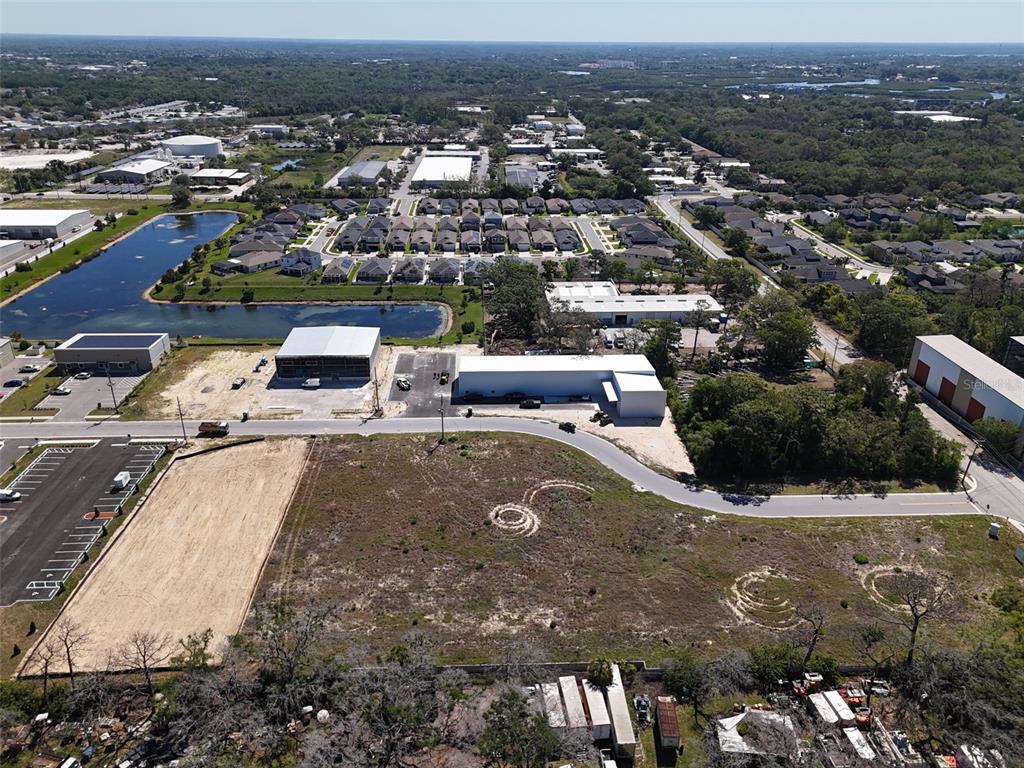 An aerial view shows a vacant lot, industrial buildings, a pond, and residential neighborhoods — 1484 NORTH BEND DRIVE, TARPON SPRINGS, FL