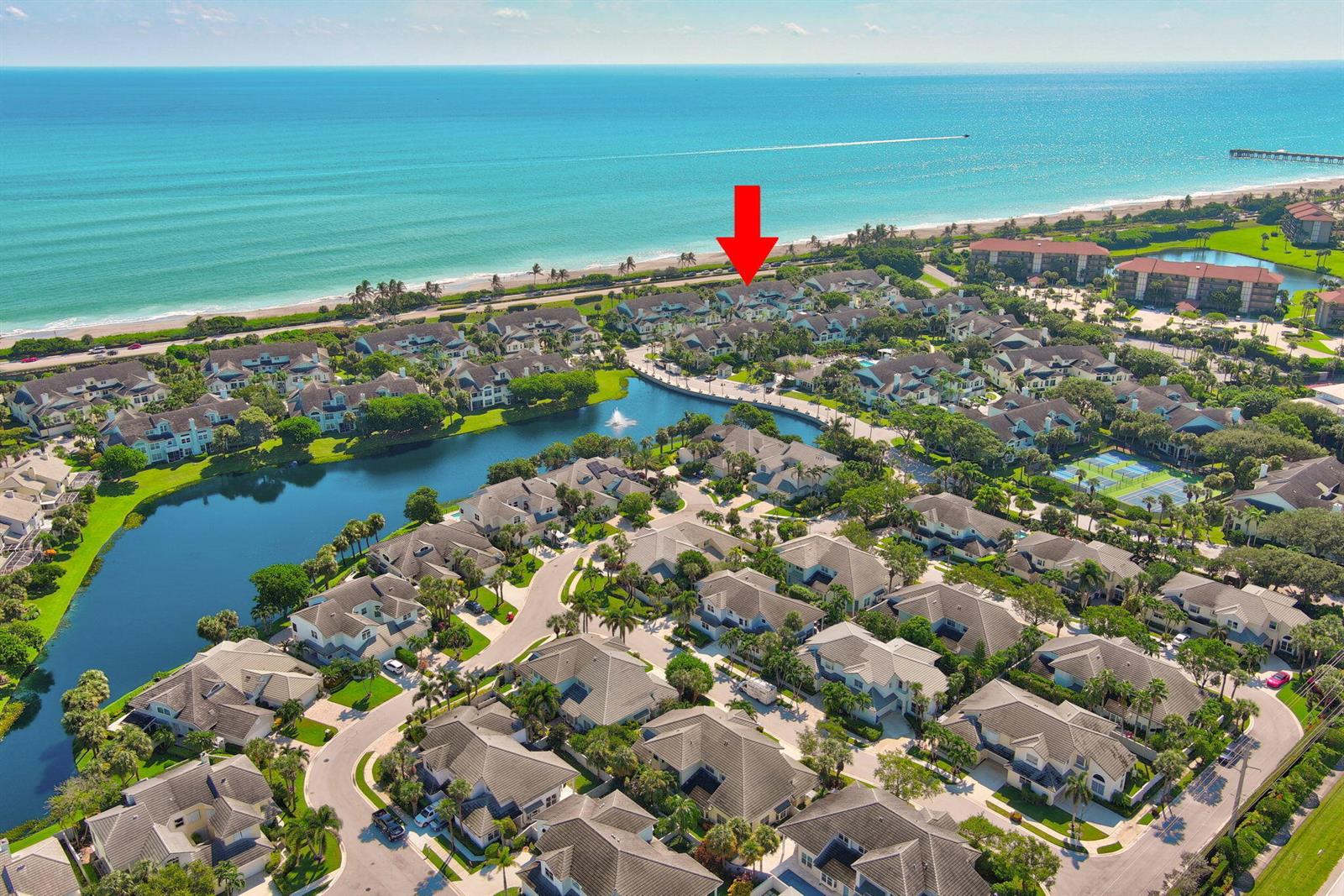 An aerial view shows a residential community with a lake, tennis courts, and oceanfront beach — 205 Mainsail Circle, Jupiter FL 33477, JUPITER, FL