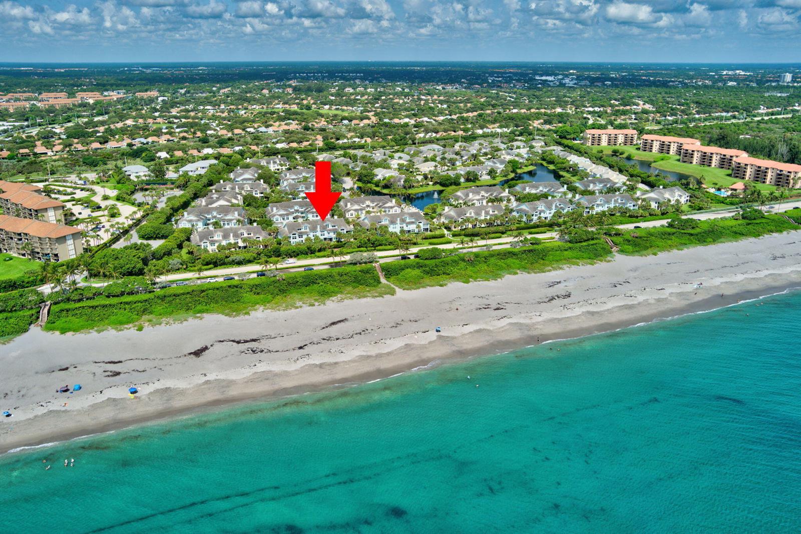 An aerial view shows a beachfront residential complex with a red arrow pointing toward buildings — 205 Mainsail Circle, Jupiter FL 33477, JUPITER, FL