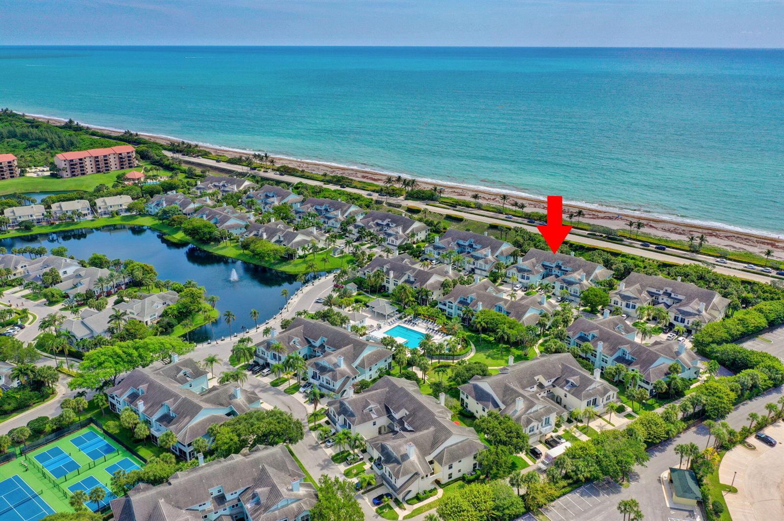 An aerial view shows a coastal residential community with a pool, tennis courts, and lake — 205 Mainsail Circle, Jupiter FL 33477, JUPITER, FL
