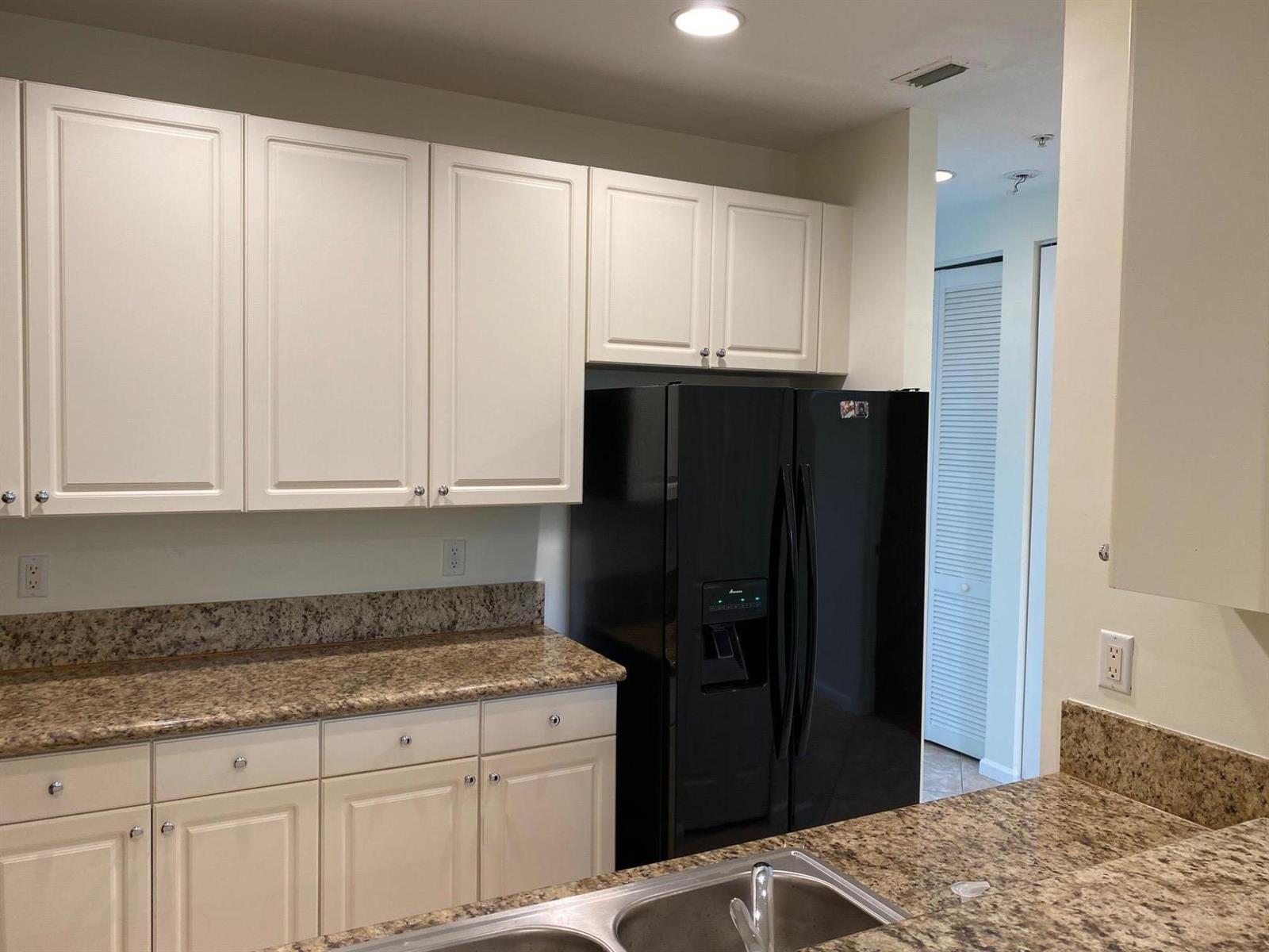 A kitchen features white cabinets, granite countertops, a black refrigerator, and a stainless steel sink — 1272 Via Fiume, Boynton Beach FL 33426, BOYNTON BEACH, FL