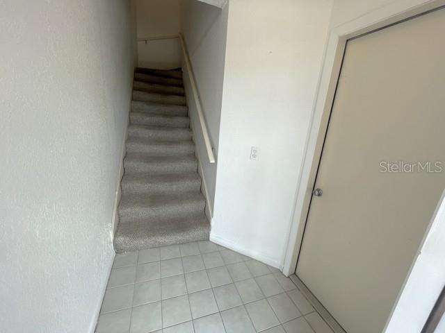 A carpeted staircase leads upward from a tiled entryway next to a closed door — 19717 GULF BOULEVARD UNIT V6, INDIAN ROCKS BEACH, FL
