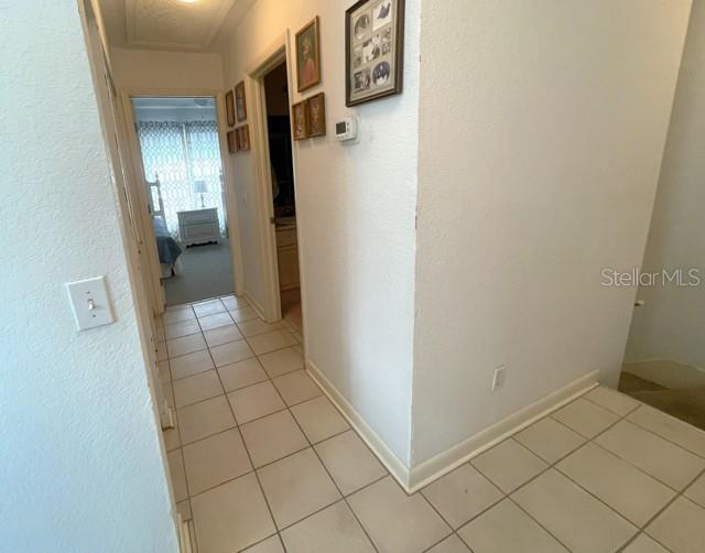 A hallway with light-colored tile flooring leads toward a bedroom with a window — 19717 GULF BOULEVARD UNIT V6, INDIAN ROCKS BEACH, FL