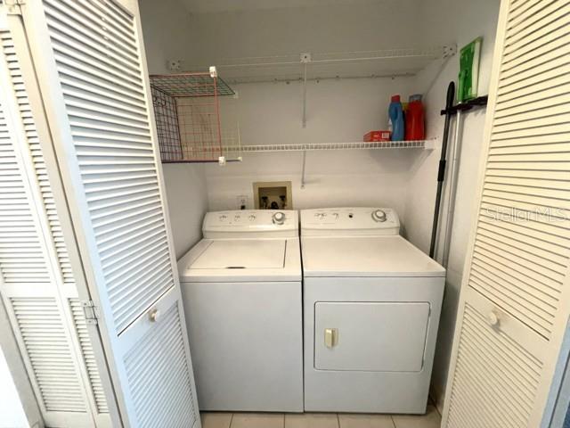 A laundry closet contains a white top-load washer and dryer beneath wire shelving — 19717 GULF BOULEVARD UNIT V6, INDIAN ROCKS BEACH, FL