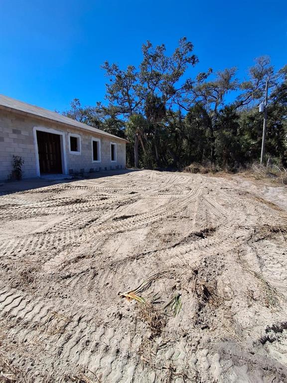 An exterior view of a concrete block building with a sandy, tire-tracked yard — 17364 COX AVENUE, PORT CHARLOTTE, FL