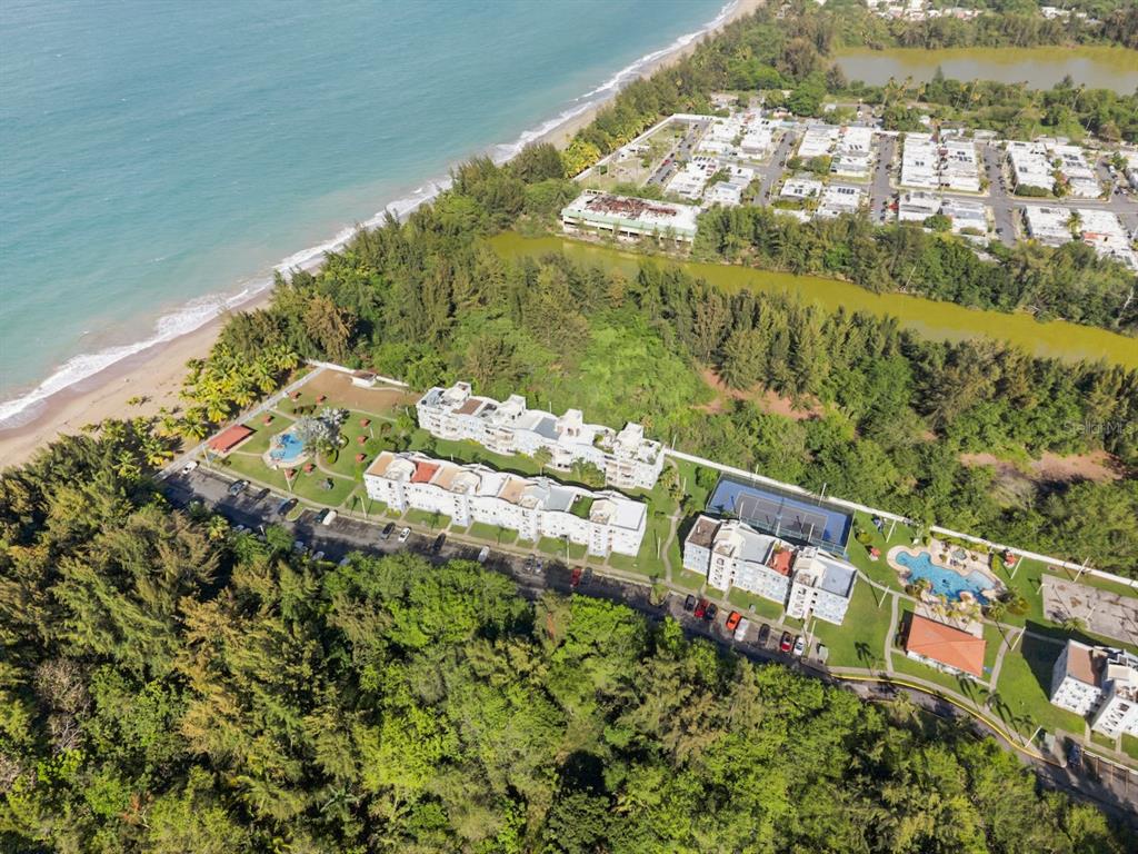 An aerial view shows a beachfront residential complex with swimming pools and tennis courts — 1 OCEAN POINT UNIT 2603, LOIZA, PR