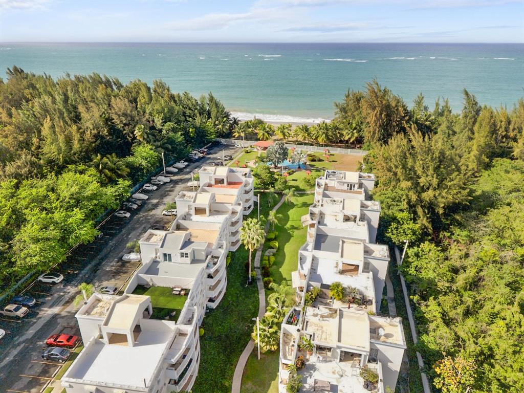 An aerial view shows two multi-story apartment buildings near a beach and ocean — 1 OCEAN POINT UNIT 2603, LOIZA, PR