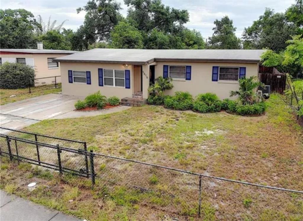 A single-story house with a tan exterior, blue shutters, and a chain-link fence — 5615 ARUNDEL DRIVE, ORLANDO, FL