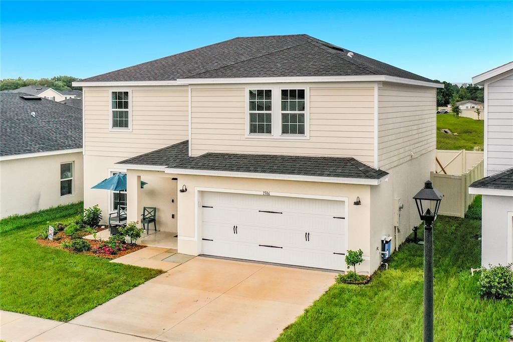 A two-story suburban house with beige siding, a two-car garage, and a concrete driveway — 1586 TEXAS AVENUE, SUMTERVILLE, FL