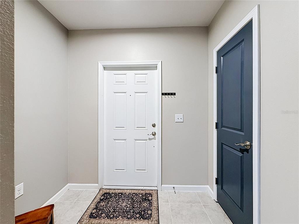 An entryway features a white front door, a dark blue interior door, and tiled flooring — 1586 TEXAS AVENUE, SUMTERVILLE, FL