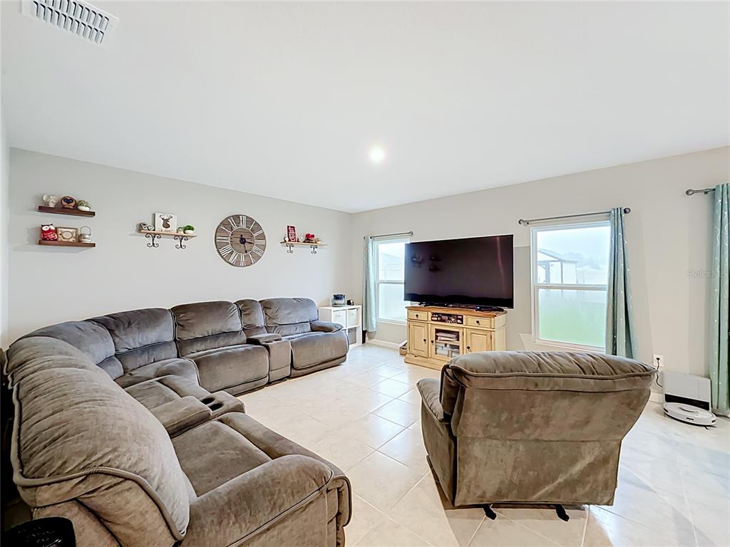 A living room features a large gray sectional sofa, a recliner, and a television console — 1586 TEXAS AVENUE, SUMTERVILLE, FL