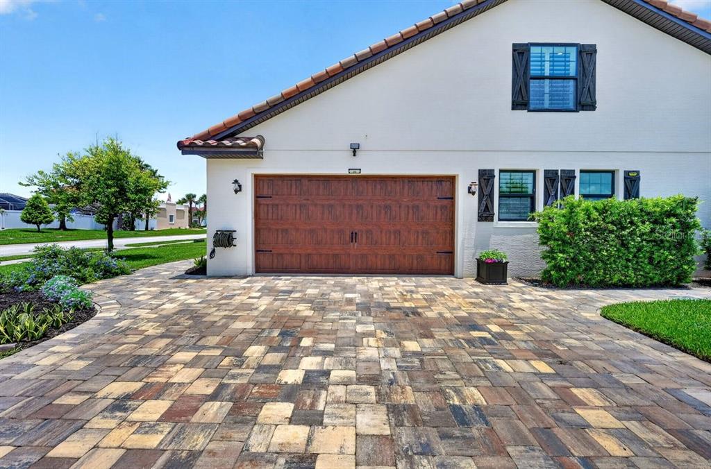 A house exterior featuring a brown garage door, a paved driveway, and a green hedge — 114 COQUINA KEY DRIVE, ORMOND BEACH, FL