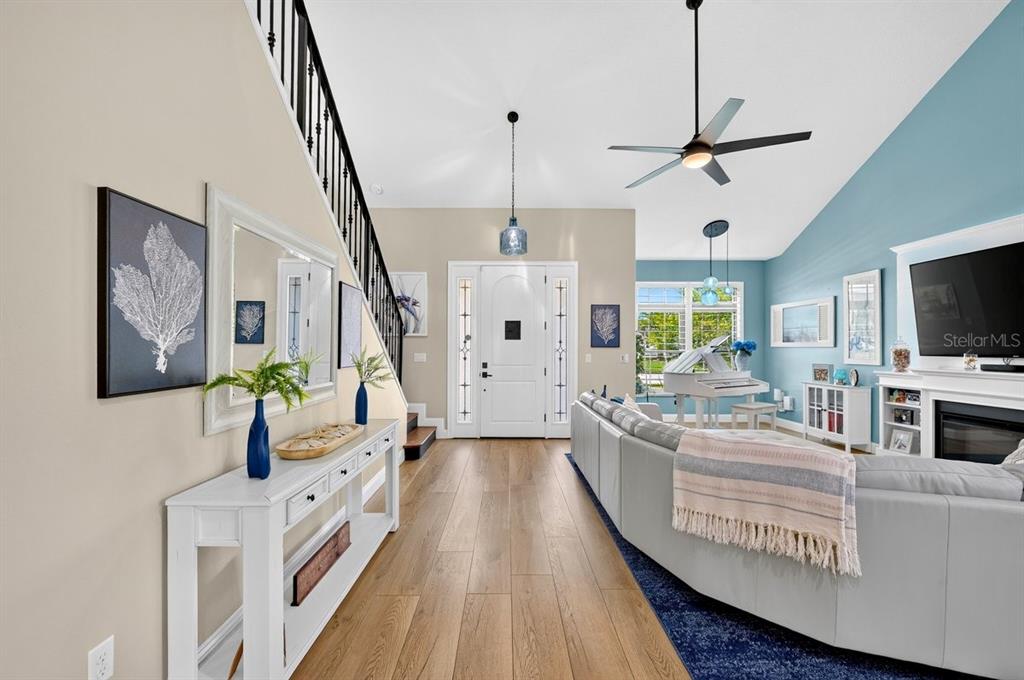A living room features a white console table, a staircase, and a white grand piano — 114 COQUINA KEY DRIVE, ORMOND BEACH, FL