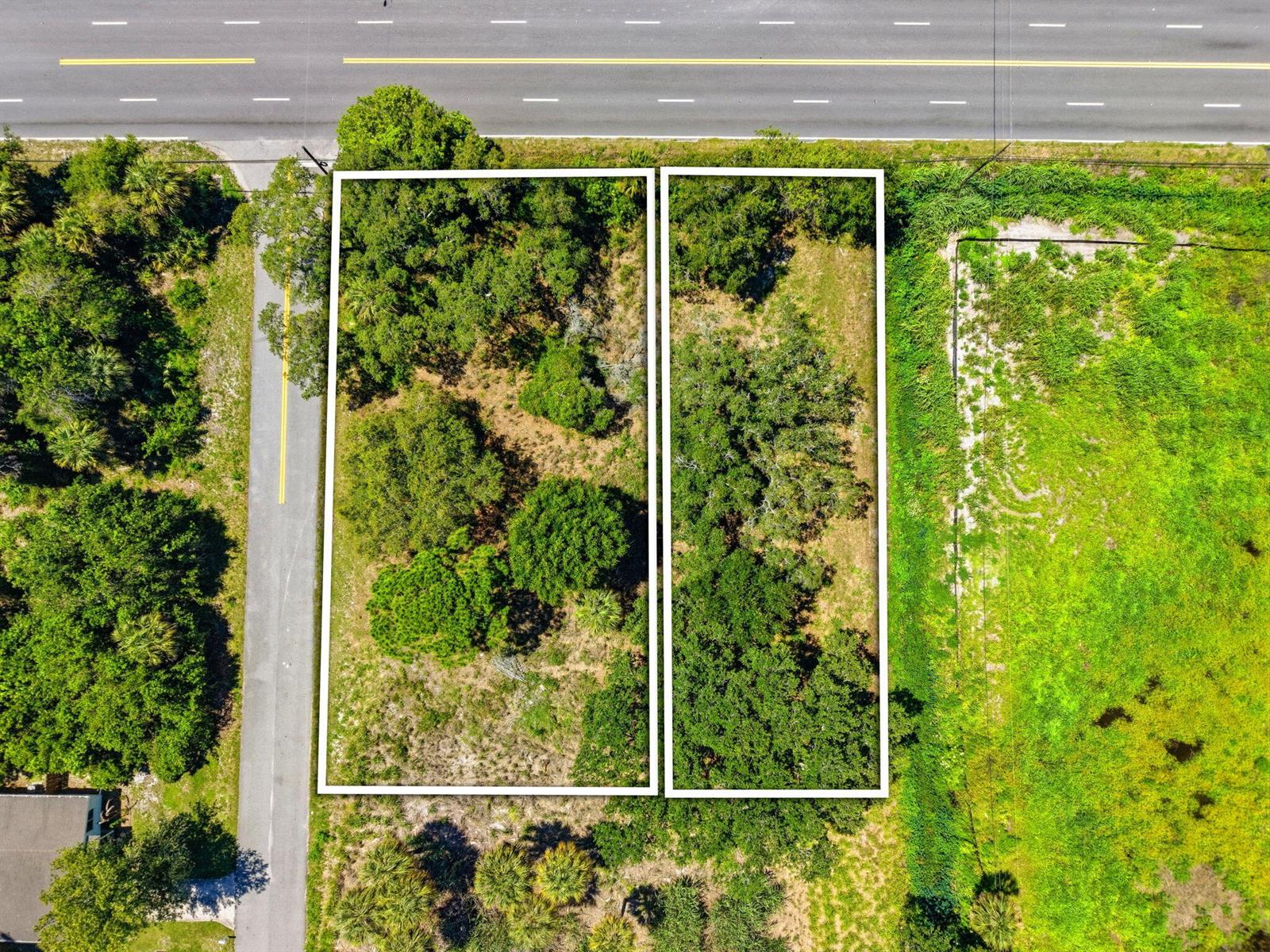 An aerial view shows two adjacent, wooded rectangular lots bordering a paved road and highway — 0 Aurora Road, Melbourne FL 32935, MELBOURNE, FL