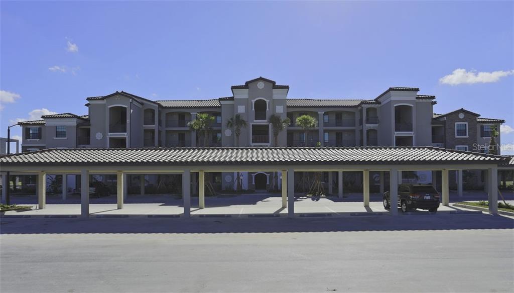 A multi-story apartment building with a covered parking structure in the foreground — 16814 VARDON TERRACE UNIT 105, LAKEWOOD RANCH, FL