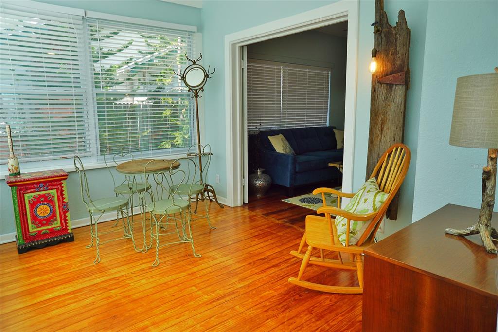 A sunroom with hardwood floors features a small bistro set, a rocking chair, and decor — 601 N OSCEOLA AVENUE, CLEARWATER, FL
