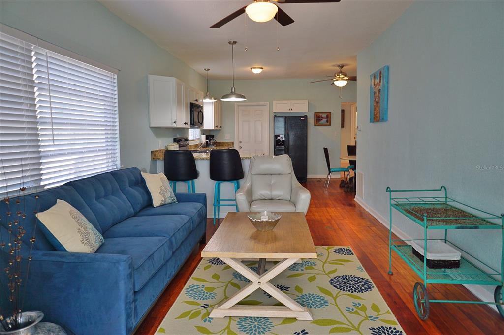 A living room with a blue sofa, coffee table, and an open kitchen with bar seating — 601 N OSCEOLA AVENUE, CLEARWATER, FL