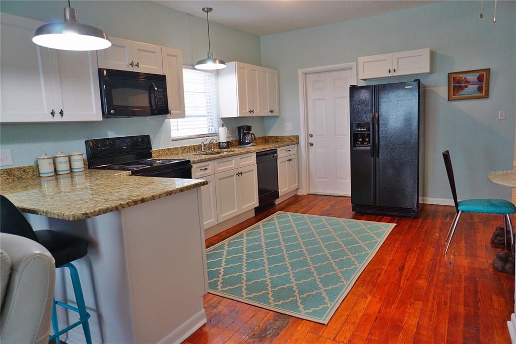 A kitchen features white cabinets, granite countertops, black appliances, and hardwood floors — 601 N OSCEOLA AVENUE, CLEARWATER, FL