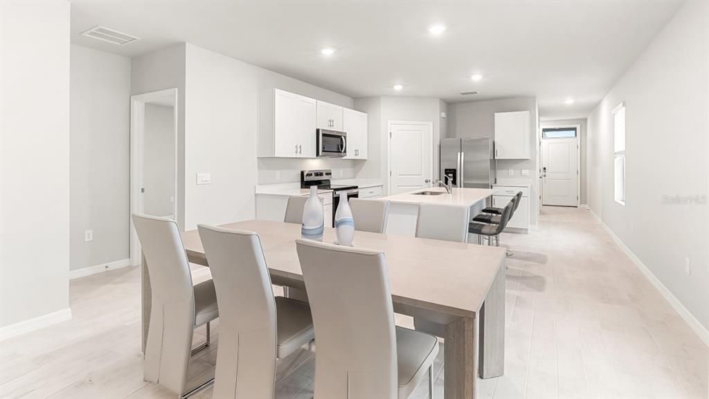 A modern kitchen with white cabinets and an island opens into a dining area — 26206 SACRED LOTUS LANE, PUNTA GORDA, FL