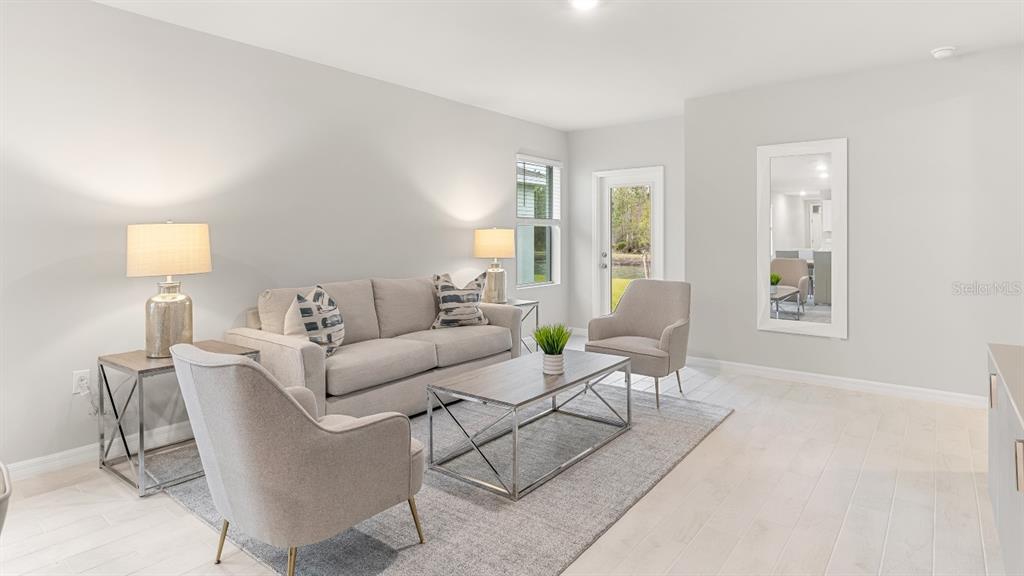 A living room features a sofa, two armchairs, a coffee table, and light-colored tile flooring — 26206 SACRED LOTUS LANE, PUNTA GORDA, FL