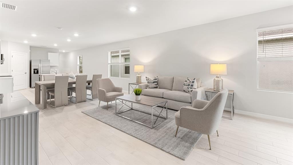 A bright, open-concept living and dining area features light tile flooring and neutral-toned furniture — 26206 SACRED LOTUS LANE, PUNTA GORDA, FL