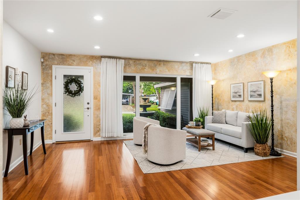 A living room features hardwood floors, textured walls, a white front door, and sliding glass doors — 2504 FORFARSHIRE DRIVE, WINTER PARK, FL