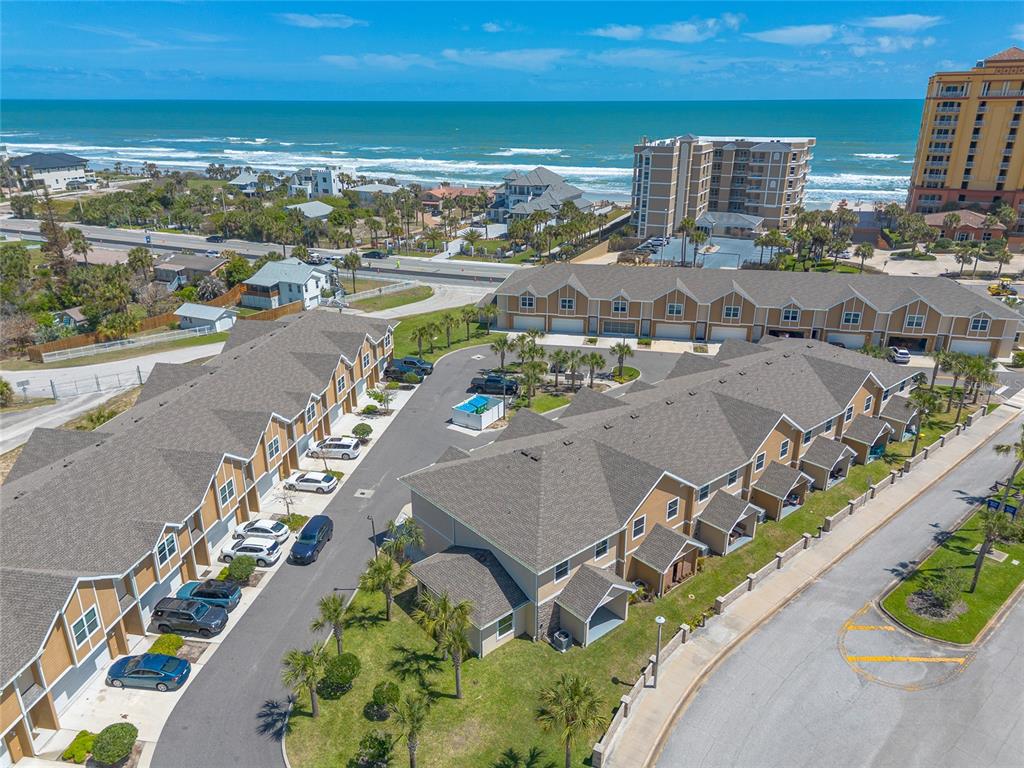 An aerial view shows a multi-unit residential complex near a beach and ocean — 119 OCEANS CIRCLE, DAYTONA BEACH SHORES, FL