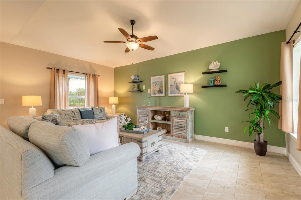 A living room features a light blue sofa, a green accent wall, and tile flooring — 119 OCEANS CIRCLE, DAYTONA BEACH SHORES, FL