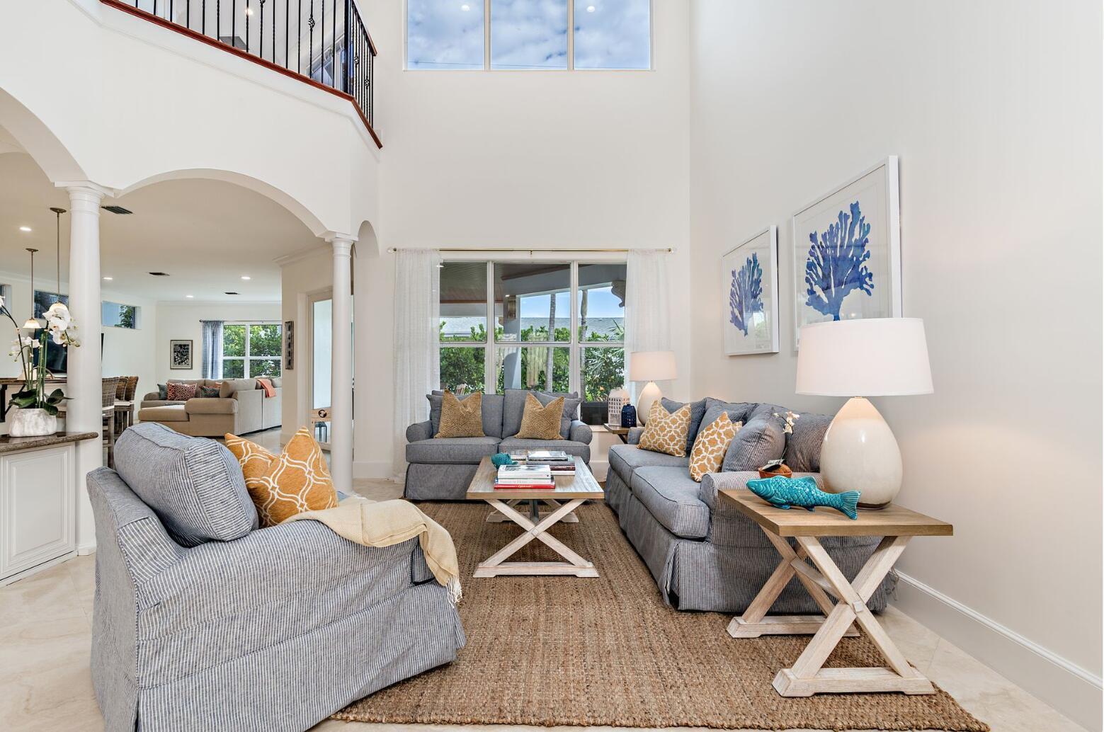 A living room features blue sofas, a wooden coffee table, and tall windows under high ceilings — 141 Gregory Place, West Palm Beach FL 33405, WEST PALM BEACH, FL