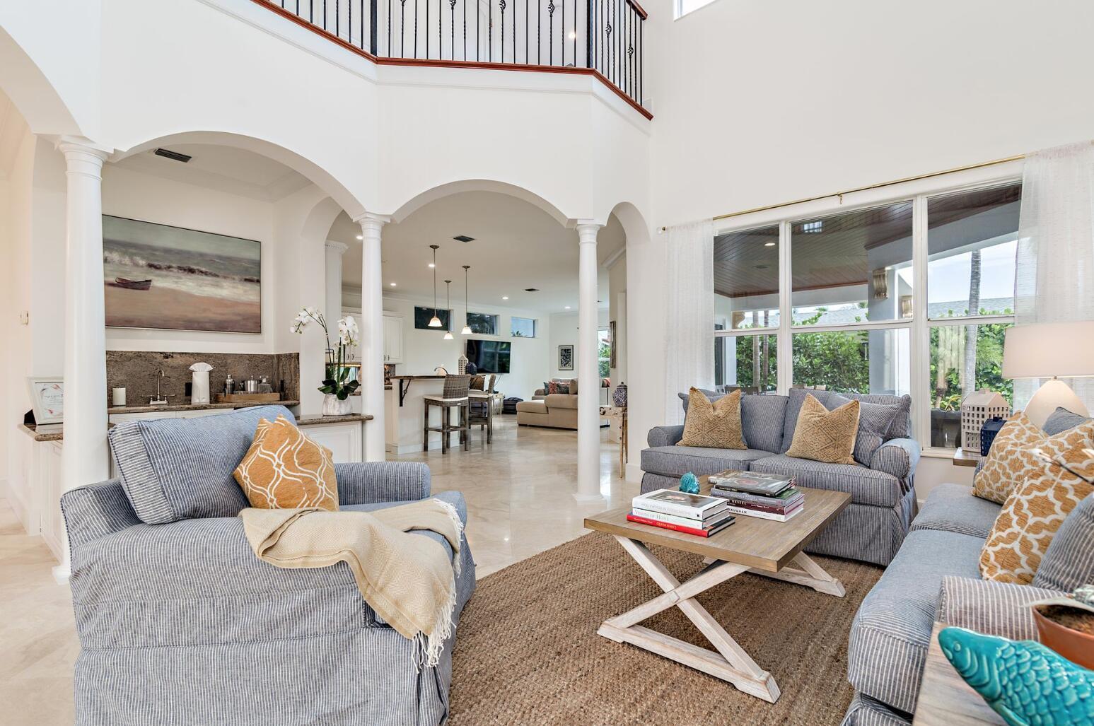 A living room with blue striped furniture, a wooden coffee table, and arched architectural columns — 141 Gregory Place, West Palm Beach FL 33405, WEST PALM BEACH, FL