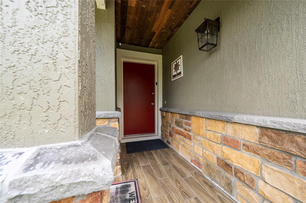 A covered entryway features a red front door, stone siding, and wood-plank ceiling panels — 3254 MOCCASIN DRIVE, KISSIMMEE, FL