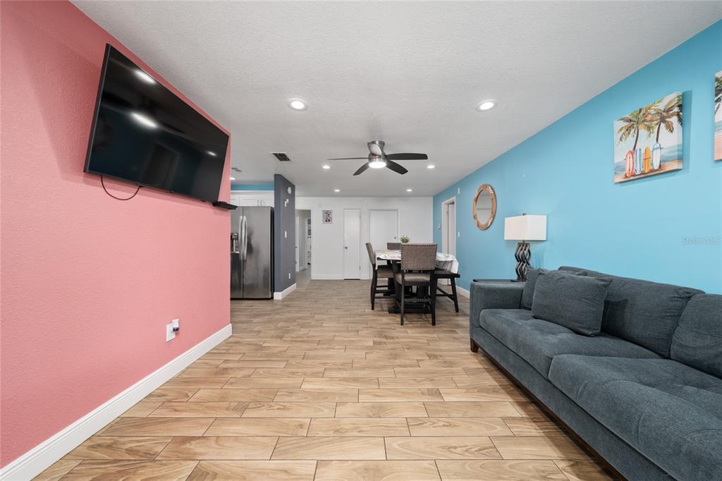 A living room with a pink wall, blue wall, grey sofa, and wood-look tile flooring — 3254 MOCCASIN DRIVE, KISSIMMEE, FL