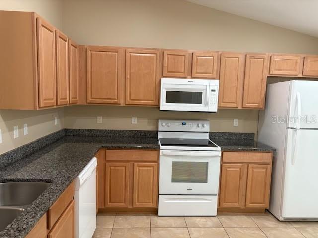A kitchen with light wood cabinets, dark granite countertops, and white appliances — 113 BRUNSWICK LANE UNIT B, PALM COAST, FL