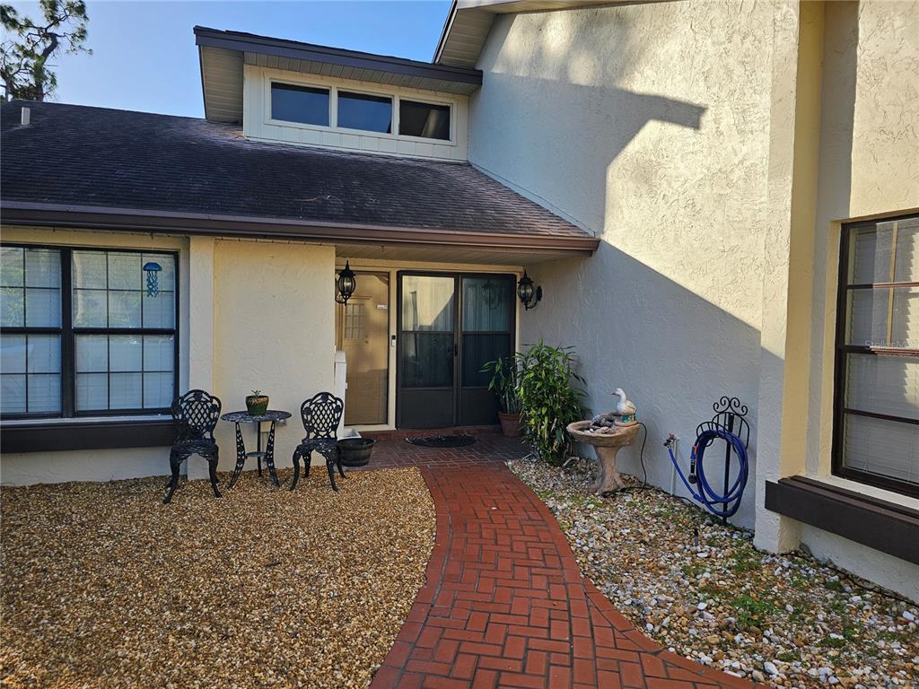 A brick walkway leads to the front entrance of a house with gravel landscaping — 4522 LA JOLLA DRIVE, BRADENTON, FL