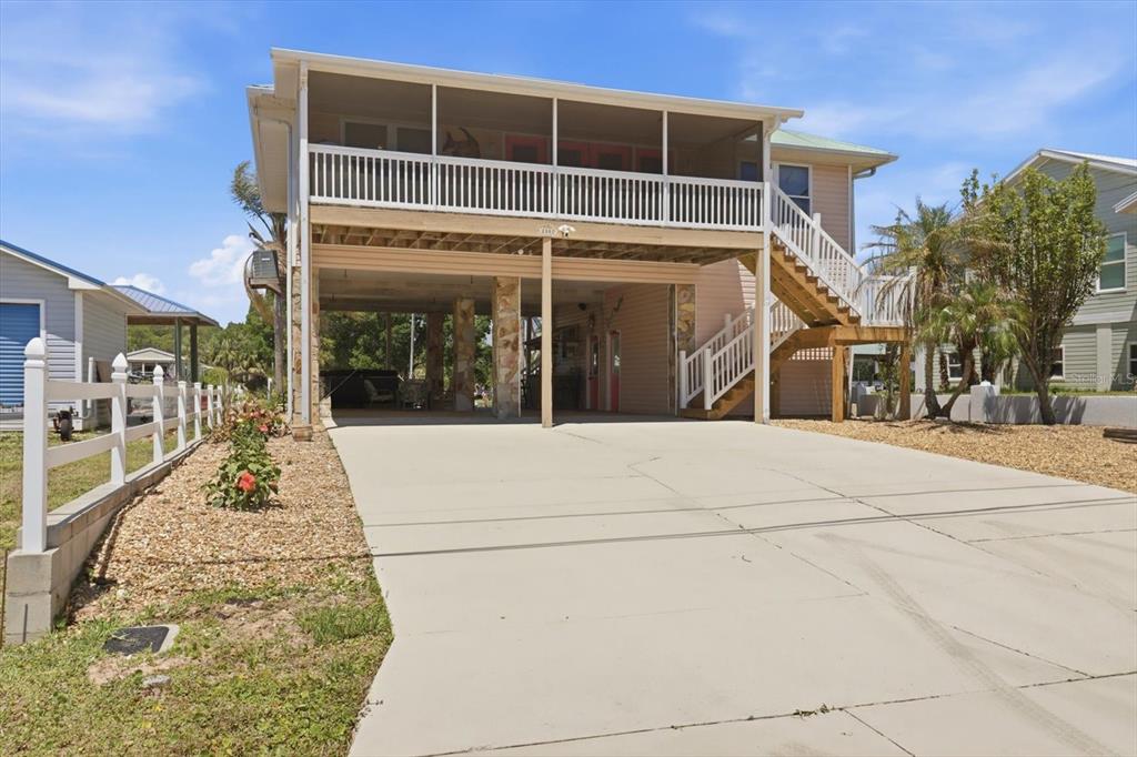 An elevated house with a screened-in porch, a concrete driveway, and wooden stairs — 2882 N COMANCHE POINT, CRYSTAL RIVER, FL