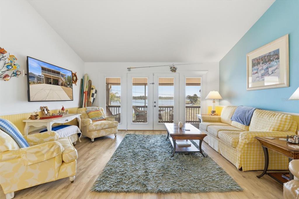 A living room features yellow patterned furniture, a blue accent wall, and glass doors overlooking water — 2882 N COMANCHE POINT, CRYSTAL RIVER, FL