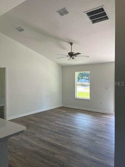 An empty living room features light-colored walls, wood-look flooring, a ceiling fan, and a window — 12129 SE 87TH COURT, BELLEVIEW, FL