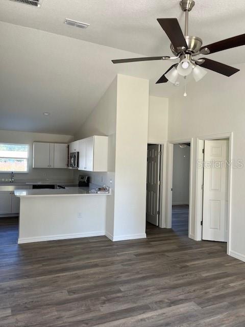 A kitchen with white cabinets and a breakfast bar overlooks a room with wood flooring — 12129 SE 87TH COURT, BELLEVIEW, FL