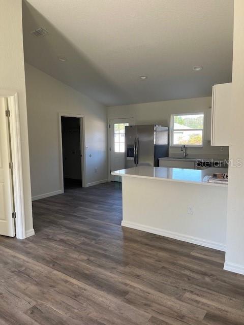 A kitchen with white cabinets, stainless steel appliances, and wood-look flooring opens to a hallway — 12129 SE 87TH COURT, BELLEVIEW, FL